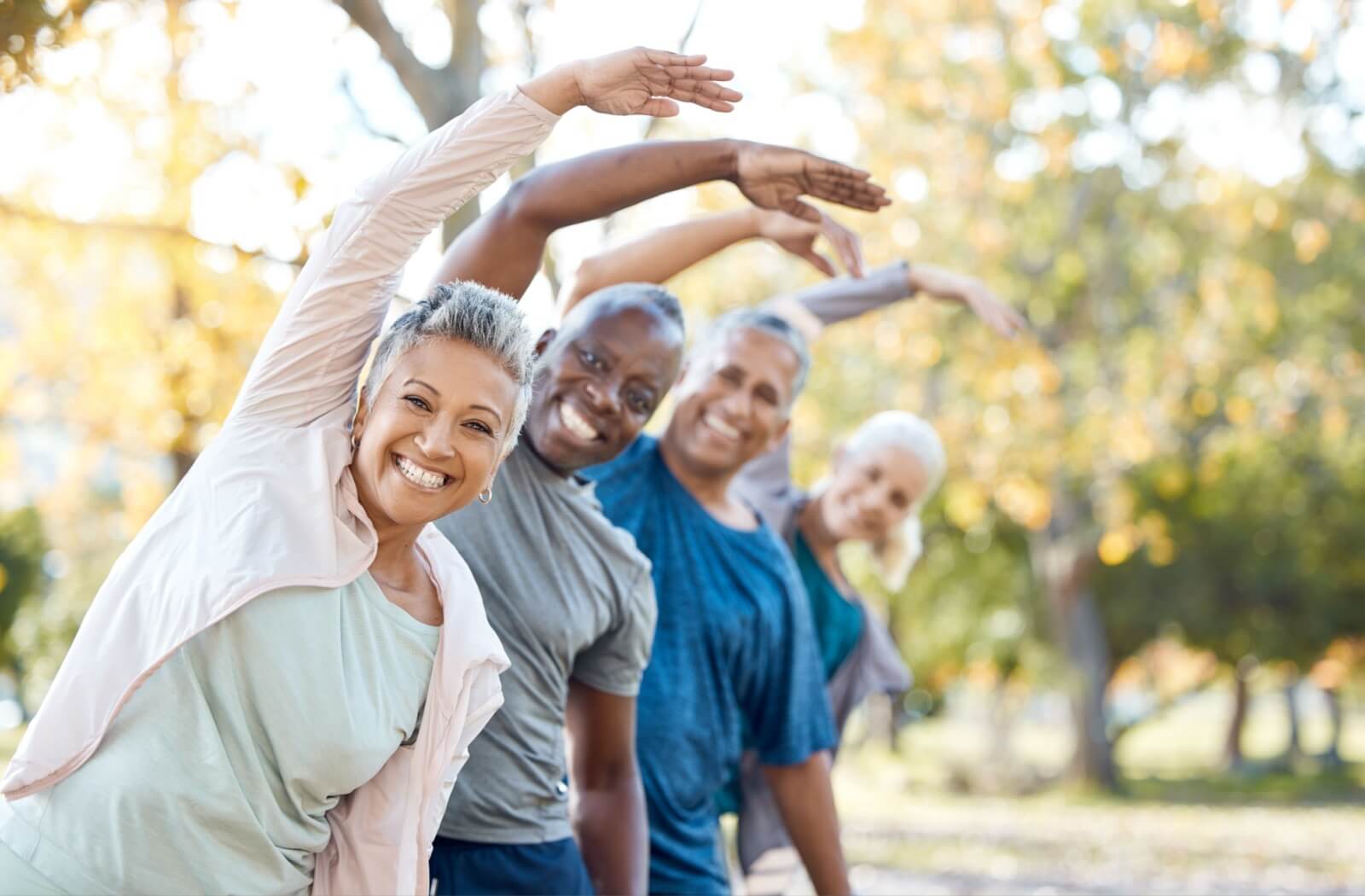 A group of older adults stretching together in the outdoors.