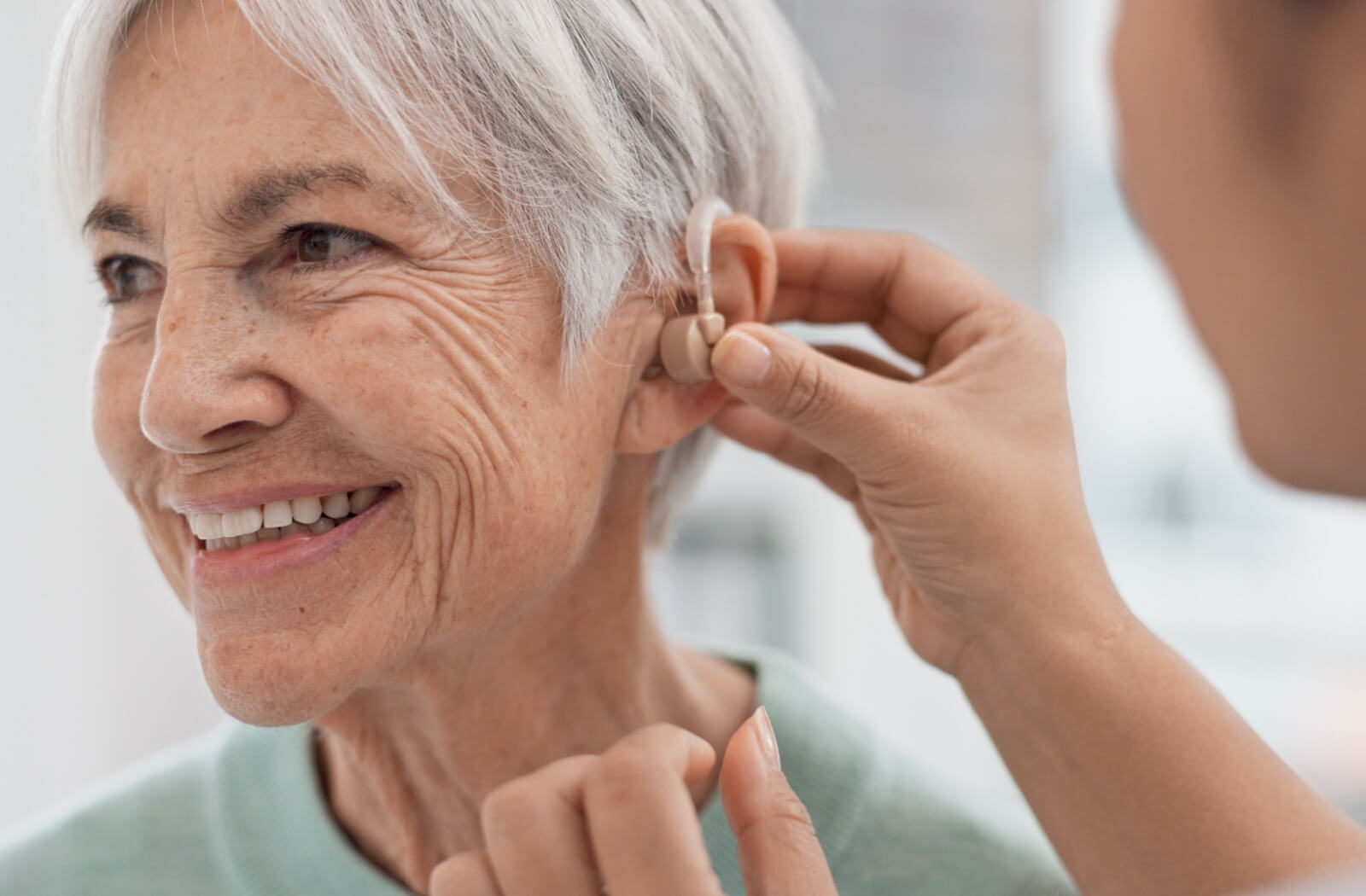 Staff assist a mature woman with her hearing aid.