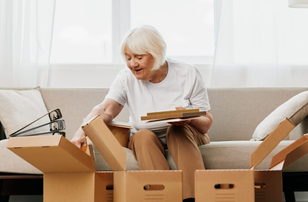 An older adult packs personal belongings into boxes to prepare for the move to a personal care home.