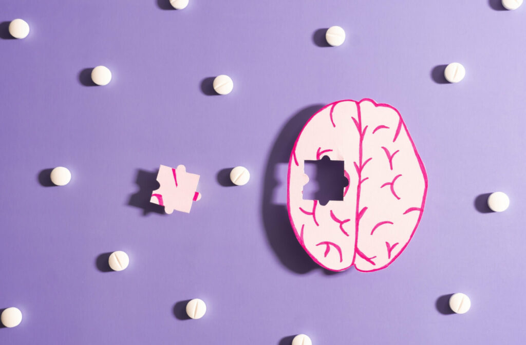 A drawing of a human brain missing puzzle piece on a purple background, surrounded by scattered pills, symbolizing the complexity and challenges of brain health and cognitive conditions like dementia.