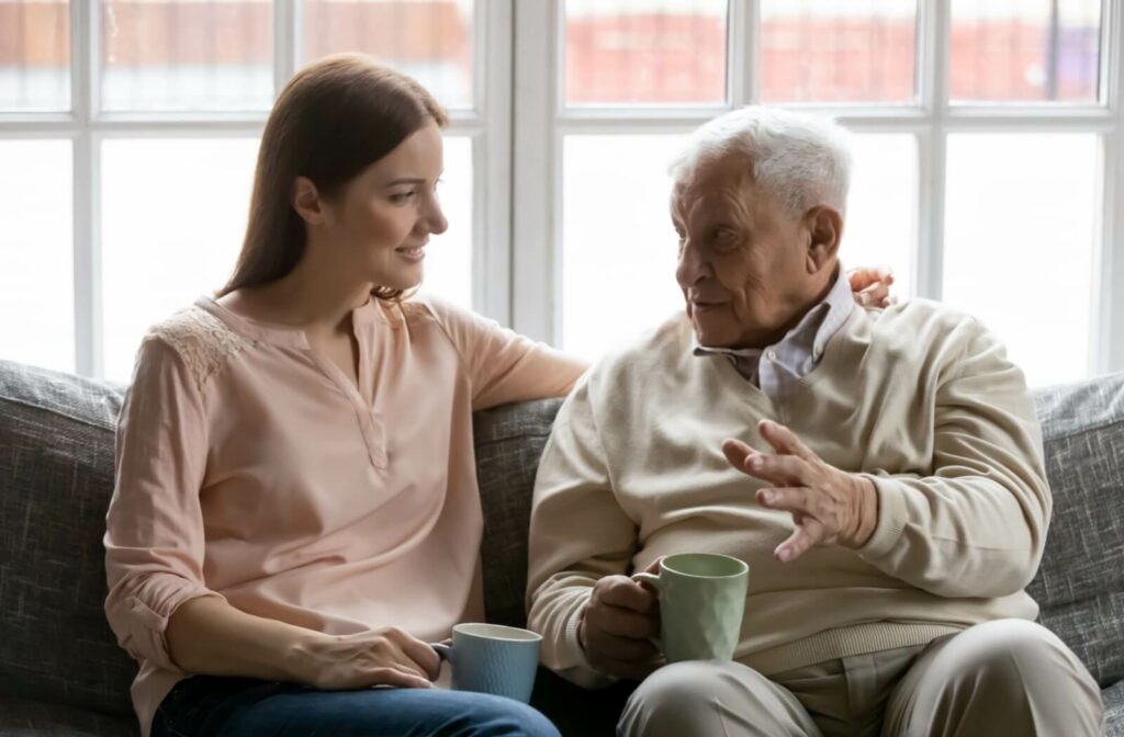 An older adult and their adult child talk over tea during a visit in senior living