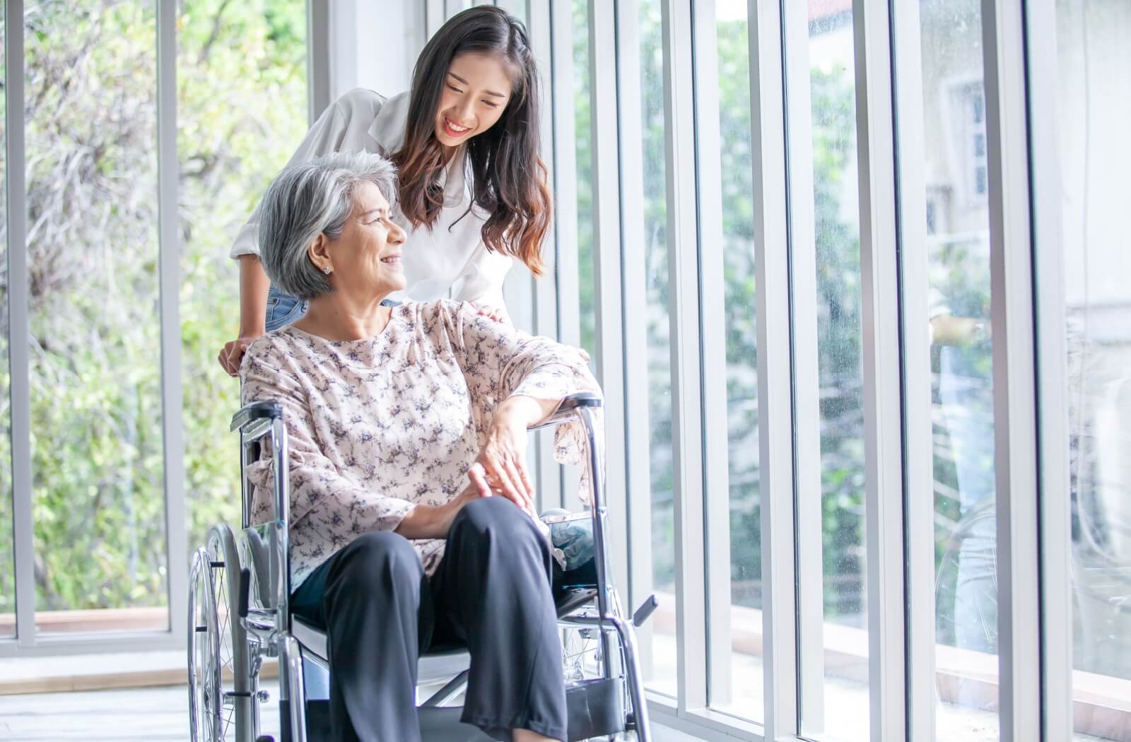 A caregiver assisting an older adult in a wheelchair.