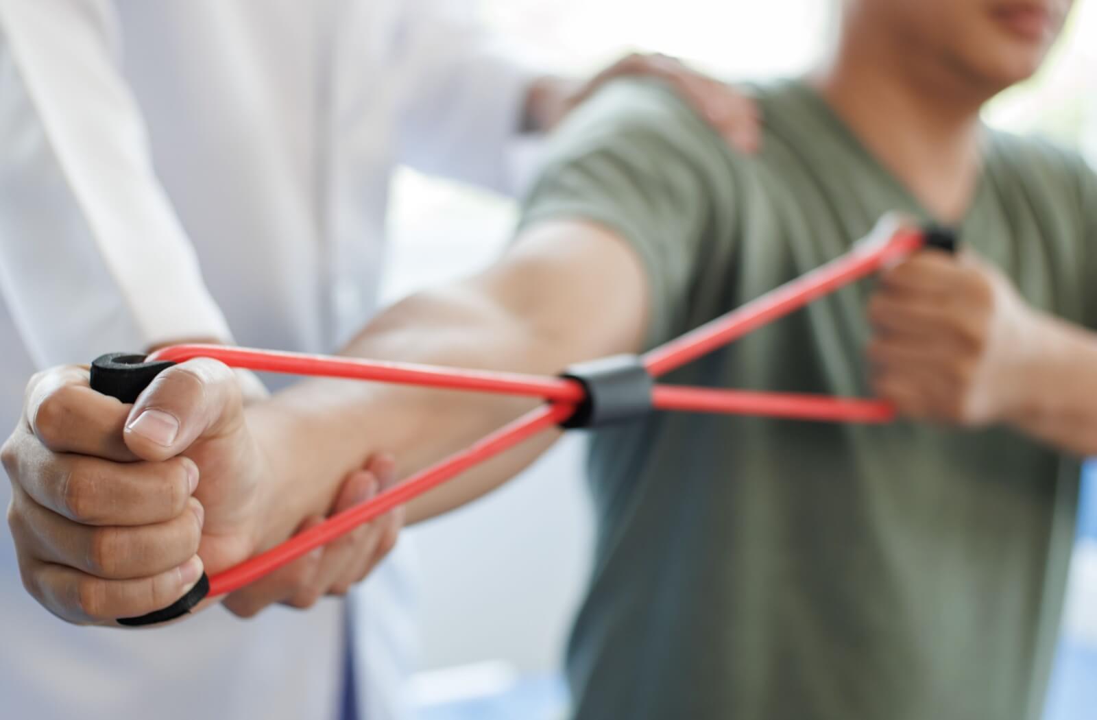A doctor helps someone with Parkinson’s Disease stretch out their arm to help reduce muscle pain