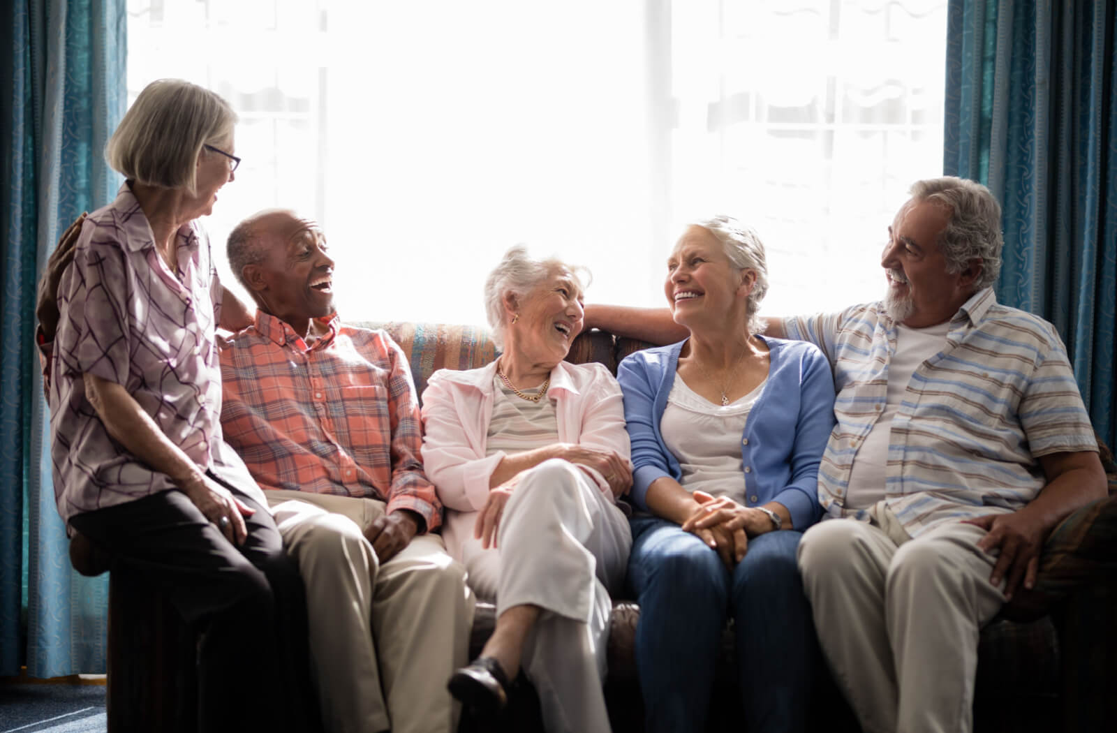 5 older adults sitting on a couch, smiling and laughing